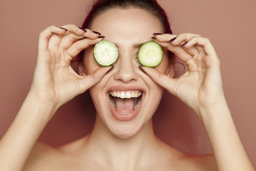 Happy young woman posing with slices of oranges on her face on r